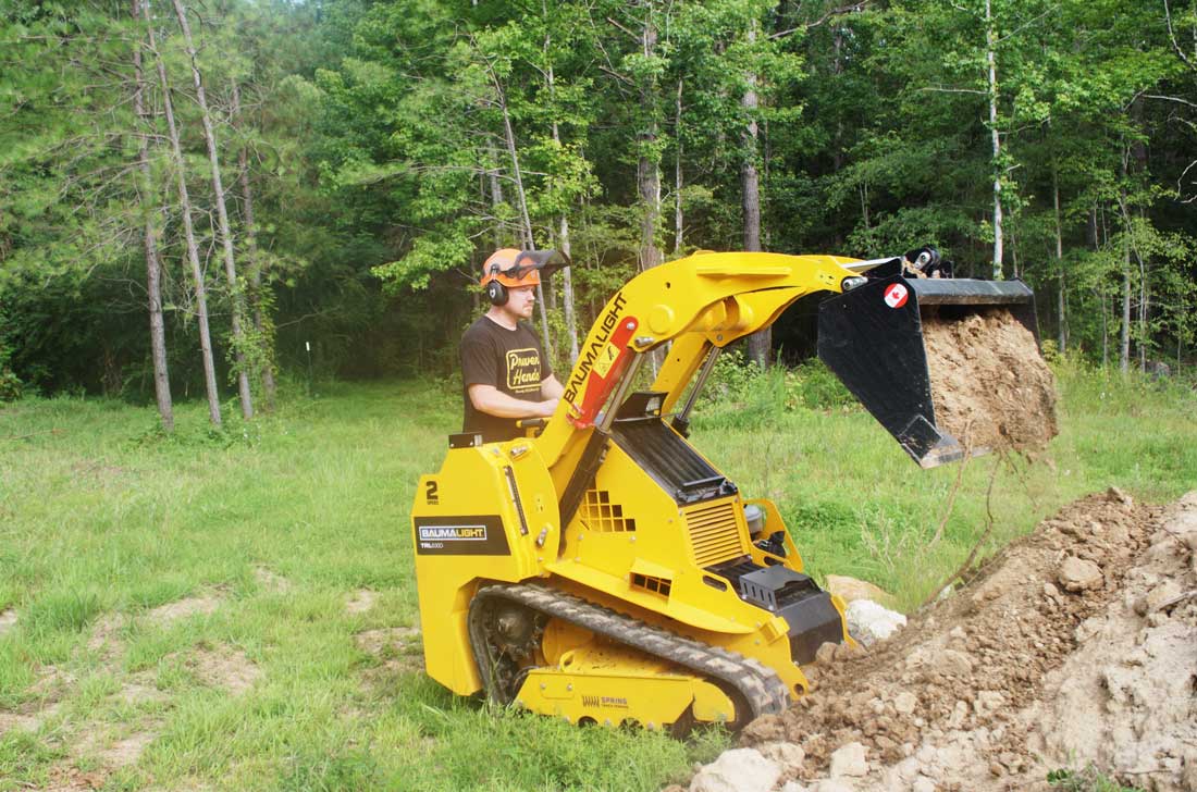 mini-chargeuse compacte sur chenilles, moteur Kubota, TRL630D chargeant de la terre avec le godet
