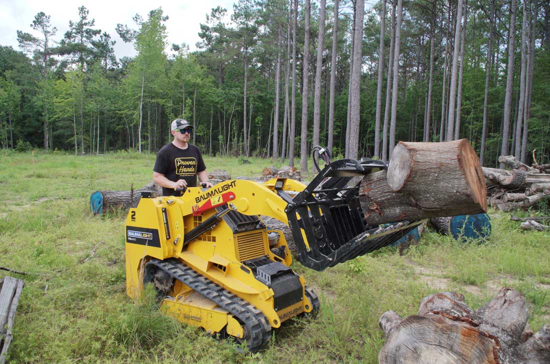 mini-chargeuse sur chenilles, moteur Kubota, pince à grumes TRL630D déplaçant une grosse bûche